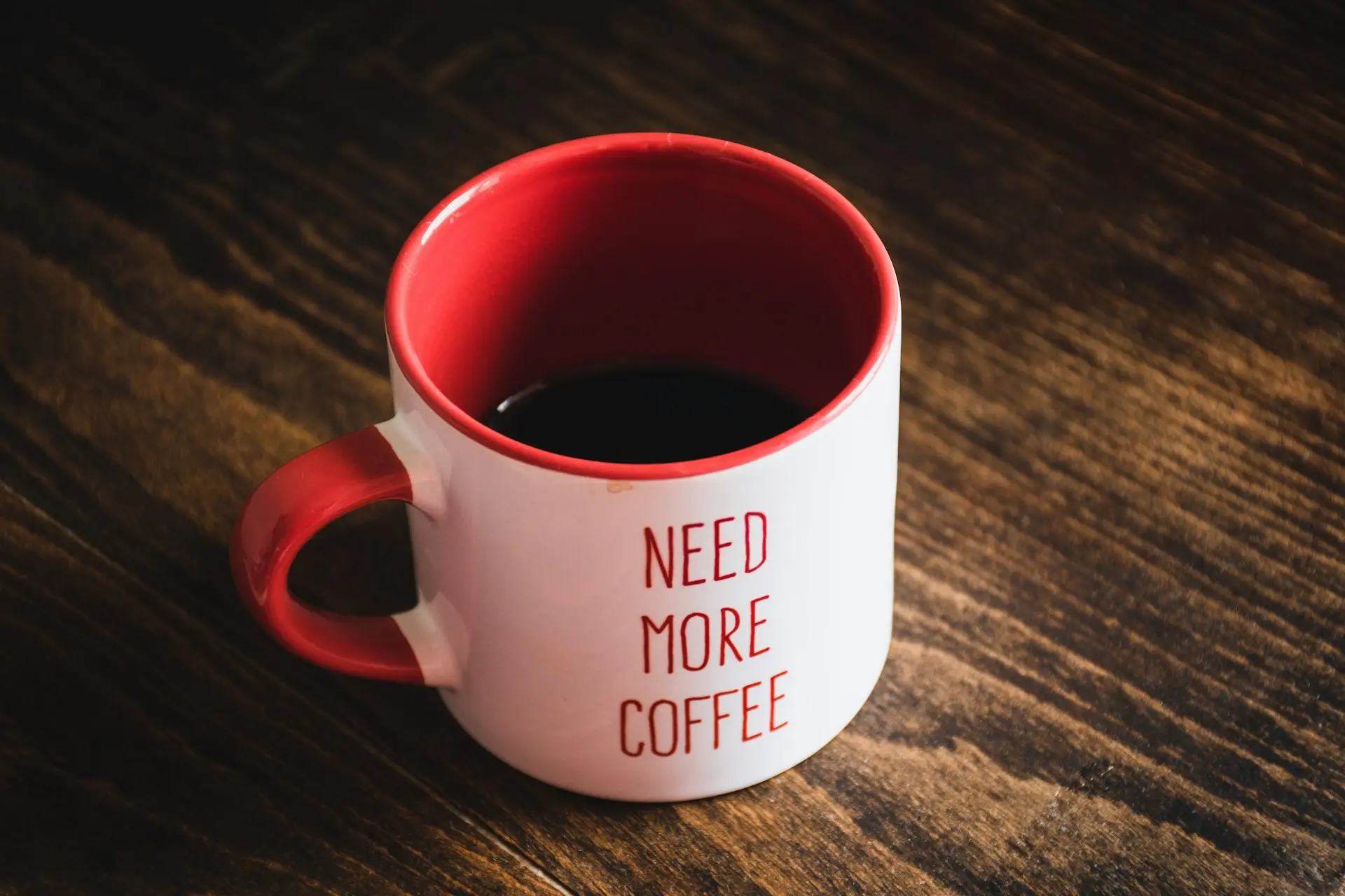 red and white ceramic mug on brown wooden table